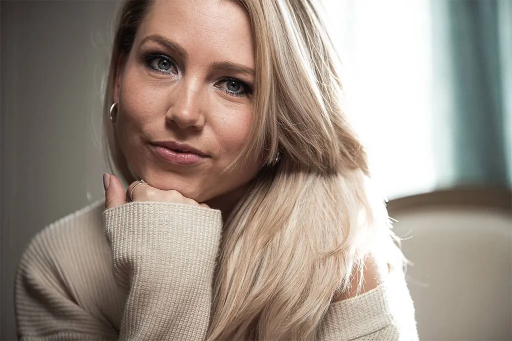 Headshot Pro Plus – www.mavvi.no – photo by Marius Volden Vakker jente med blå øyenskygge i stue på salong med neve under haka og poserer for et headshot. Foto.